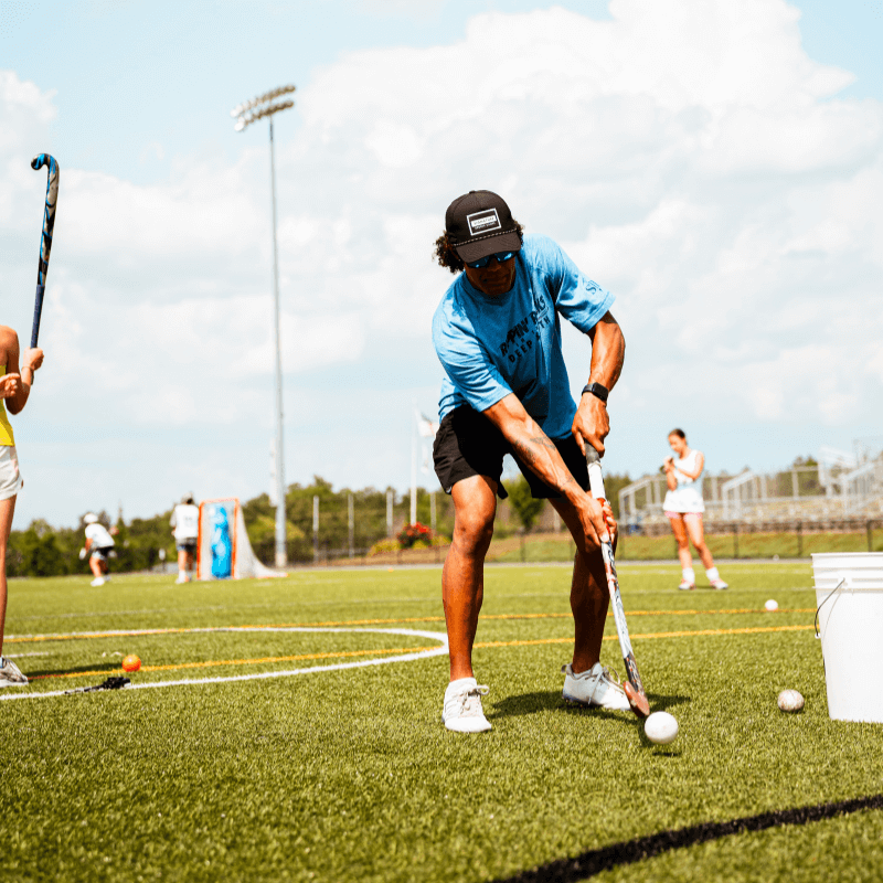 Coach at Signature Sports Camp demonstrating field hockey drills during practice