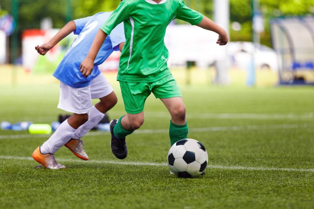 young soccer players kicking a soccer ball during a game on an outdoor field