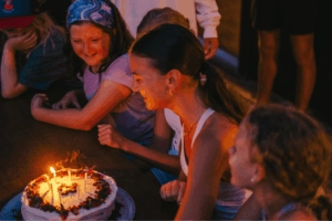 Girl blowing out birthday cake candles at sports camp