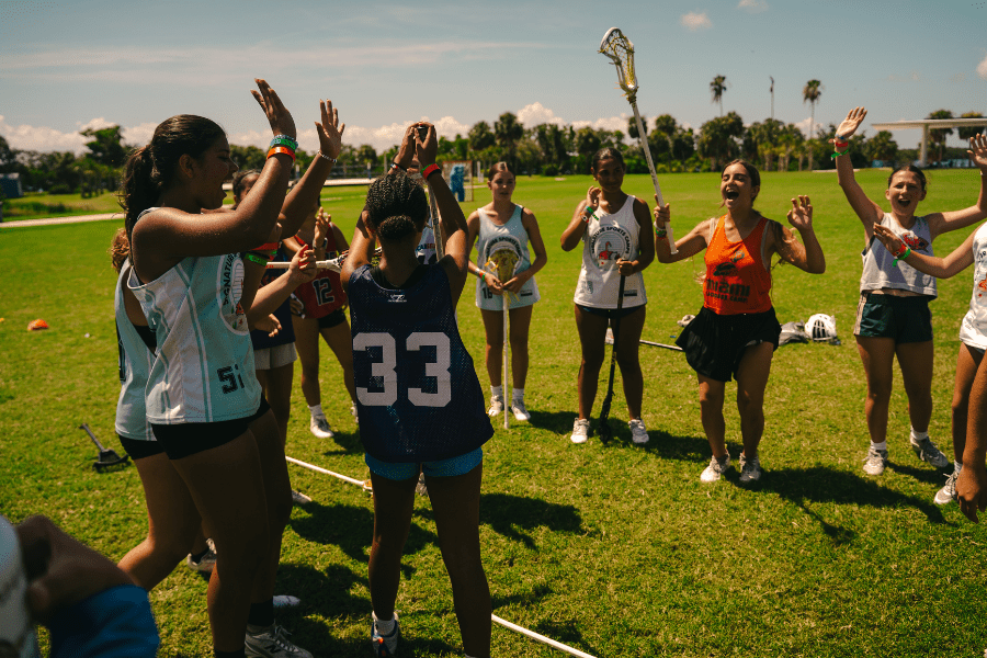 group of girls lacrosse players listening to their coach at camp