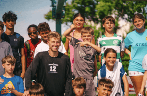 Kids at signature sports camps stand next to a professional soccer player who came to coach them.