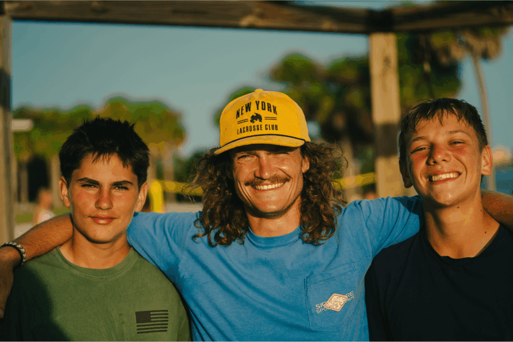 Overnight sports camp counselor smiles with two coaches in training