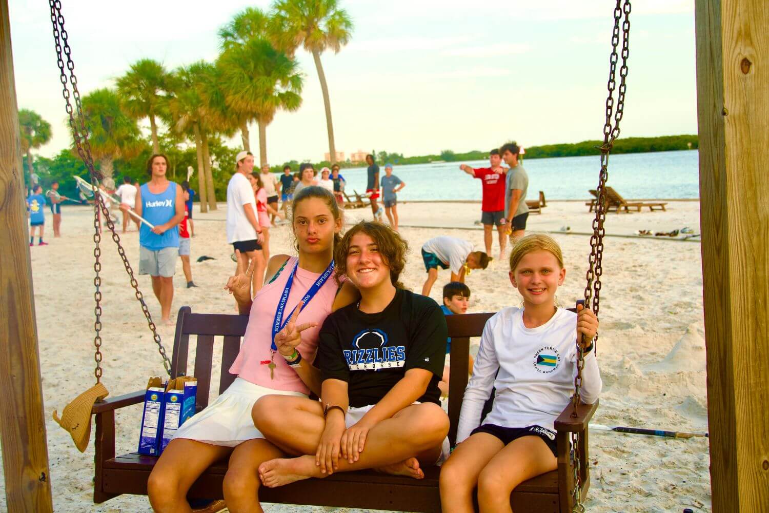 Three girls sitting on a bench having fun at the beach during summer sports camp