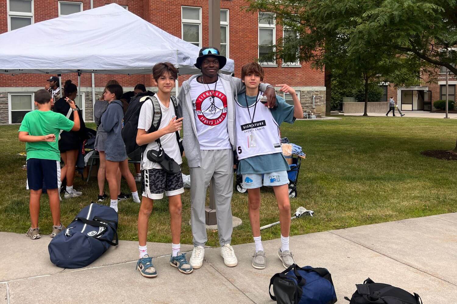 Two campers locked arms with a summer camp counselor at camp check-in