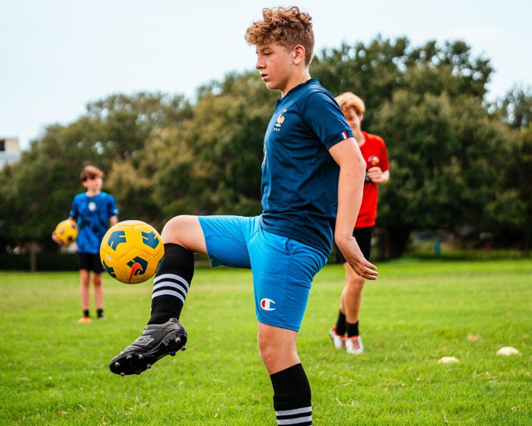 Boy dribbling yellow soccer ball at signature sports camps