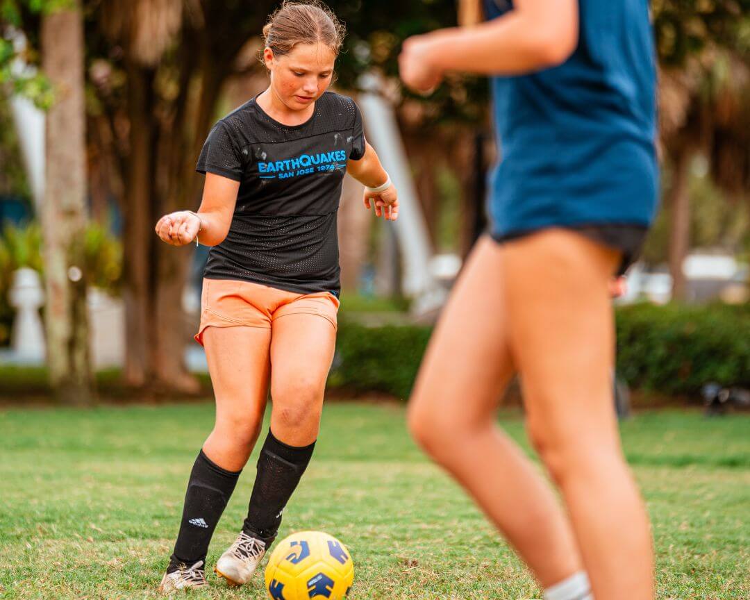 Girl practicing soccer dribbling while at sports camp