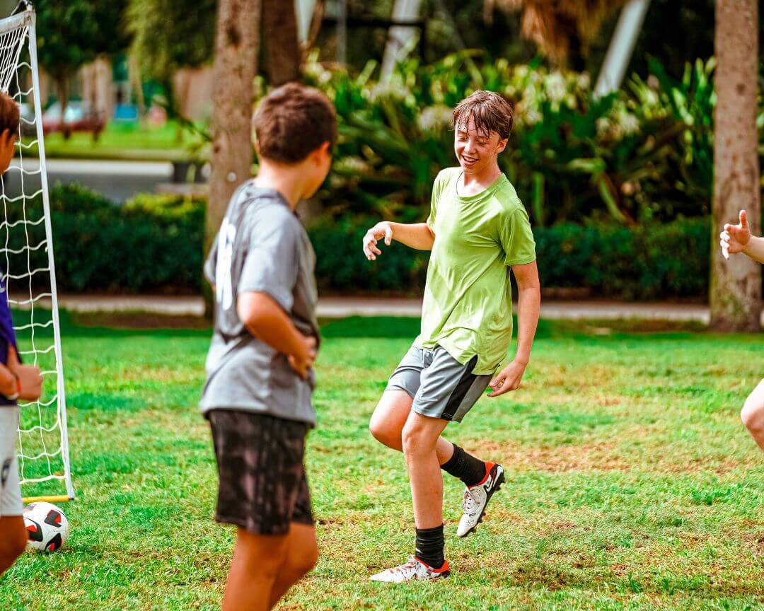 Boys smiling as they play soccer at signature sports camp