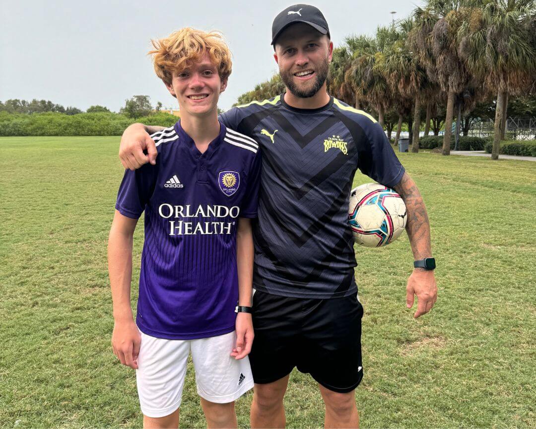 Pro soccer player Nicky Law poses for a photo with a male youth athlete