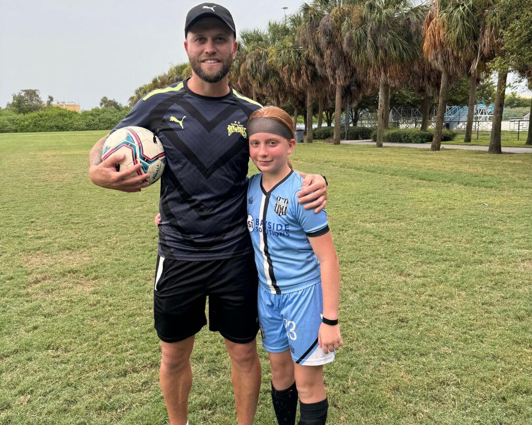 Pro soccer player Nicky Law poses for a photo with a female youth athlete
