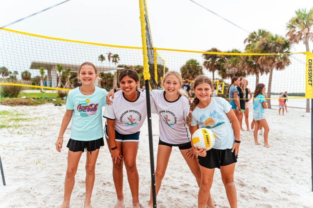Four girls at Signature Sports Camp pose for a photo on the beach