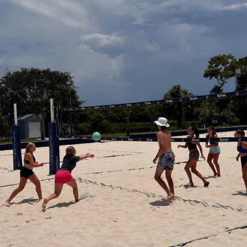 coed group playing beach volleyball at camp