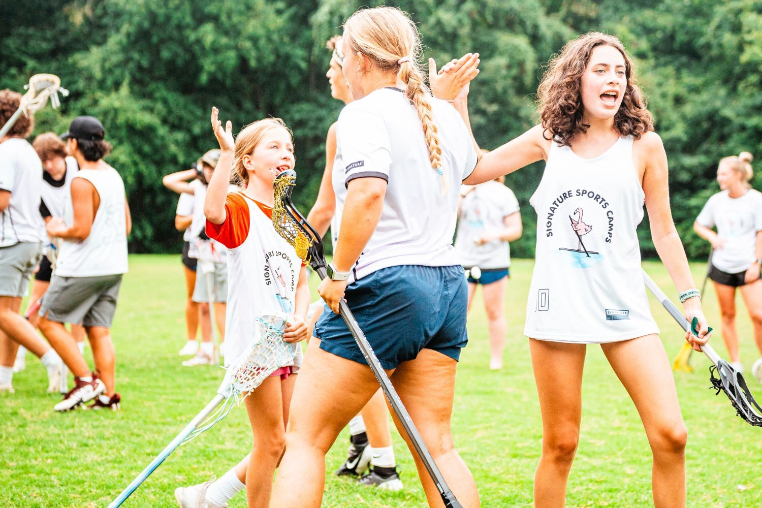 Coach high fiving girls of all ages at lacrosse practice