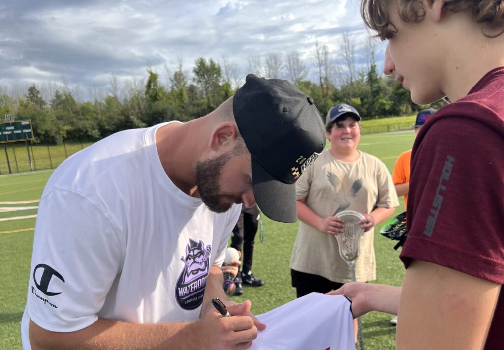 PLL Professional Lacrosse Player Ryland Rees signs a high school lacrosse player's jersey.