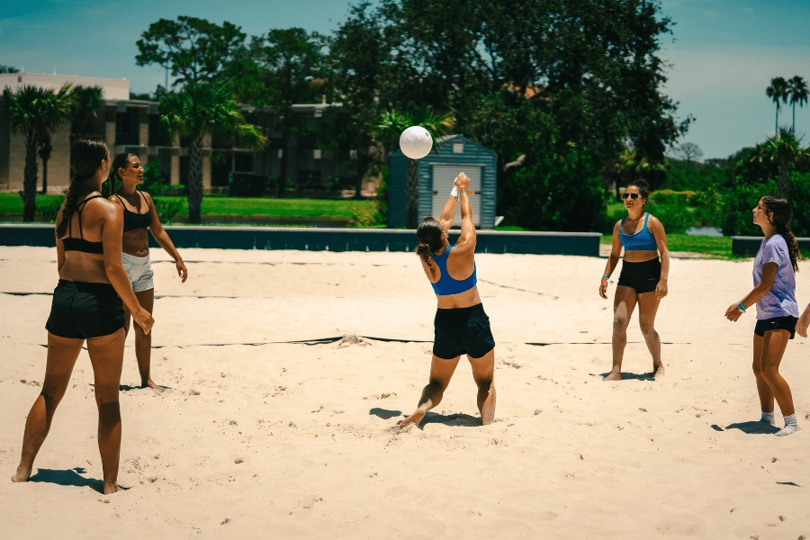 girls at overnight sports camp playing beach volleyball