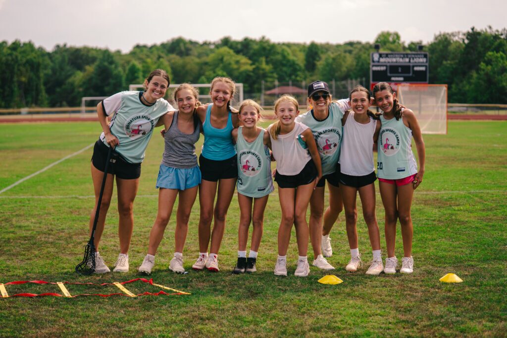 Signature sports camp coaches and athletes smile on the field during training