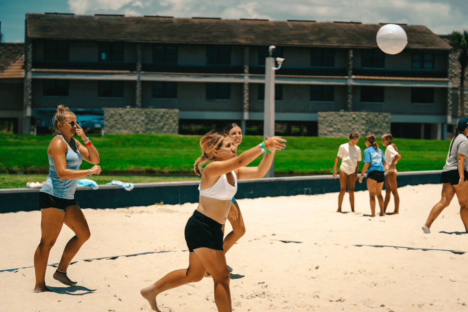 Girl hitting a volleyball during a summer camp game of beach volleyball