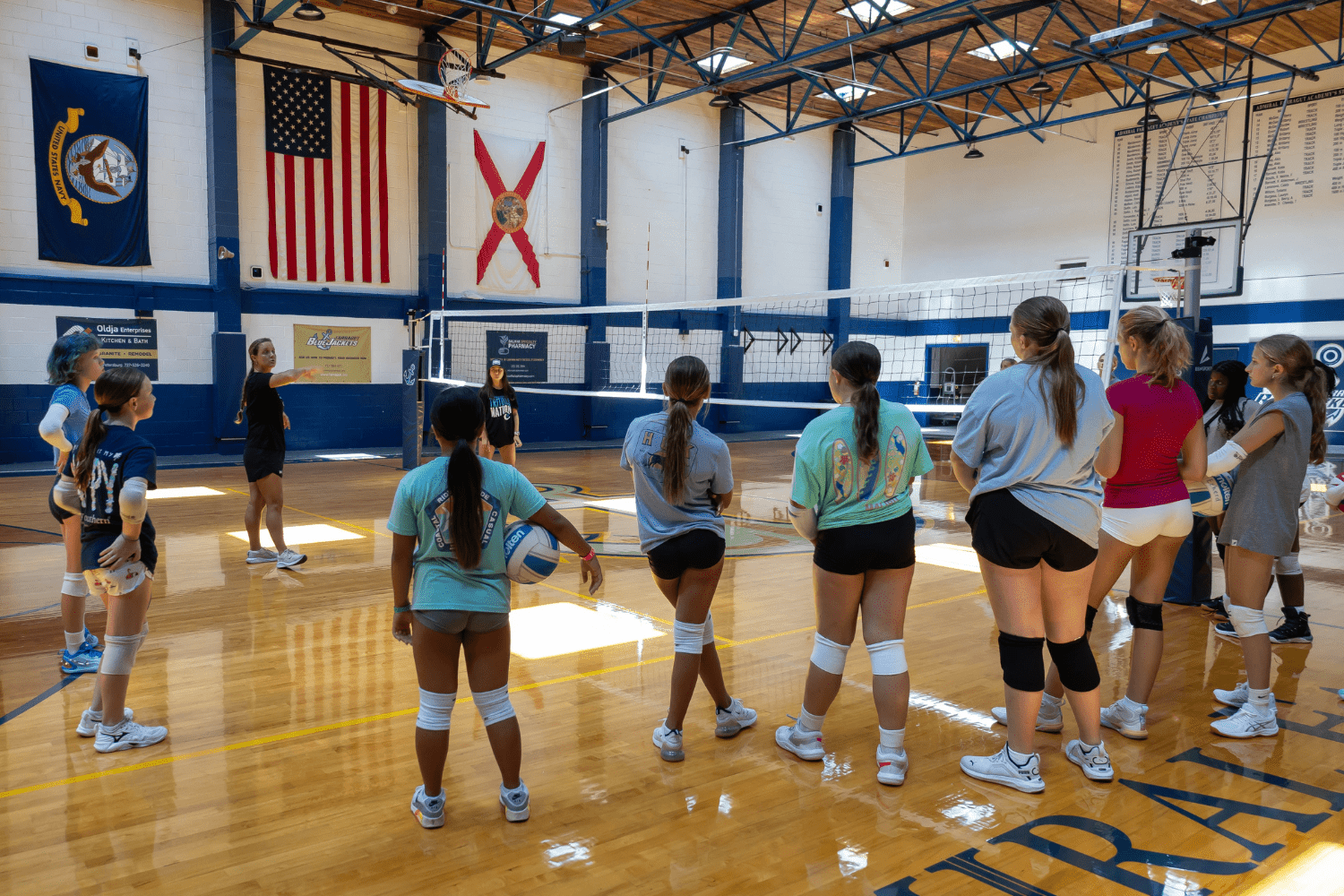 Girls listening to a coach during volleyball practice at Signature Sports Camps
