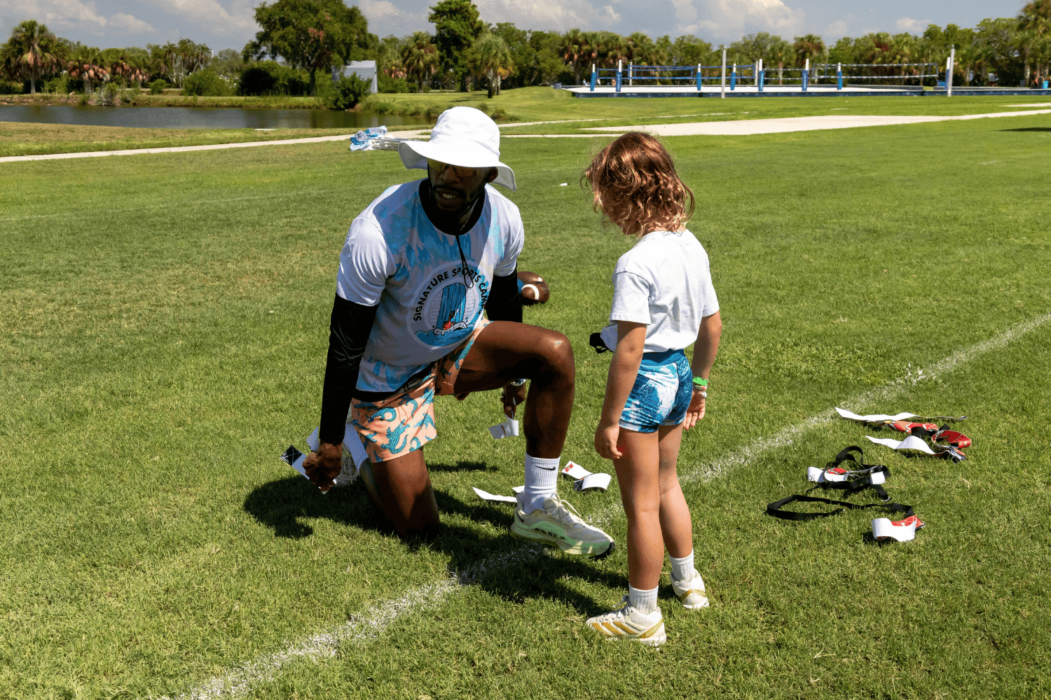 Coach speaking to a young camper during Signature Sports Camps flag football practice session