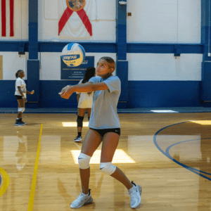 Girl at Signature Sports Camps practicing volleyball fundamentals indoors
