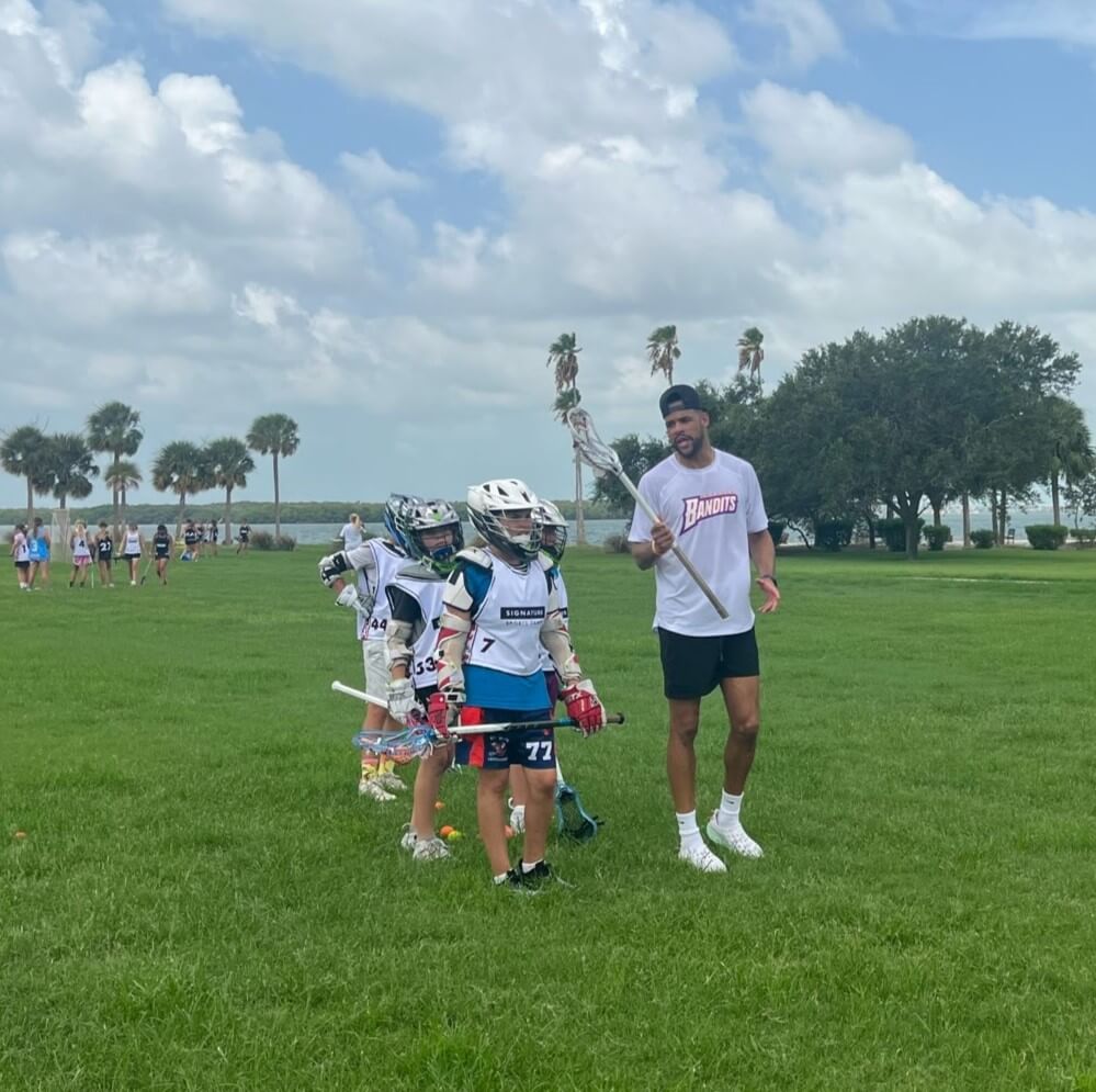Professional lacrosse player coaching a group of boys at lacrosse summer camp