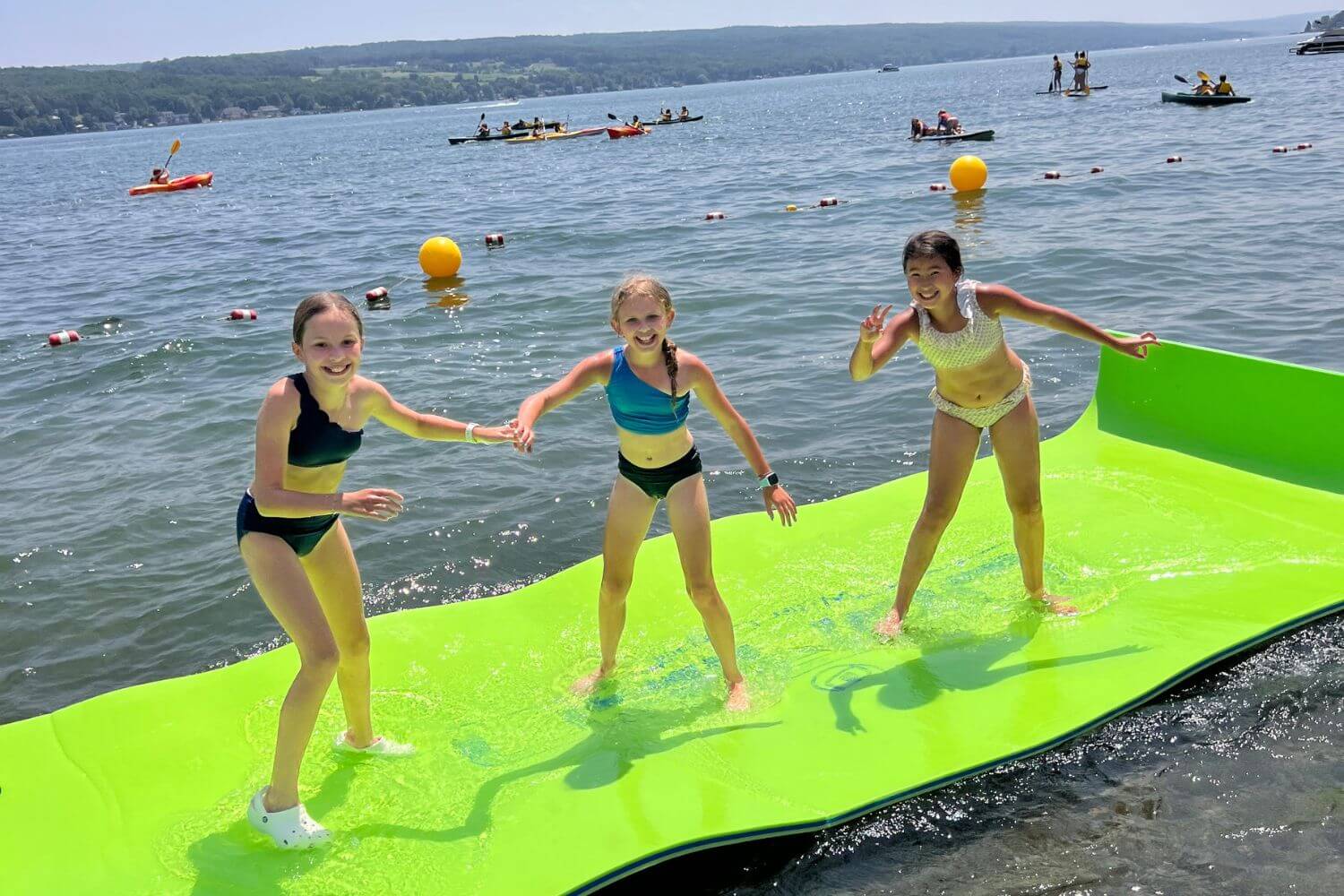 A group of young lacrosse campers are standing on a lily pad in the water