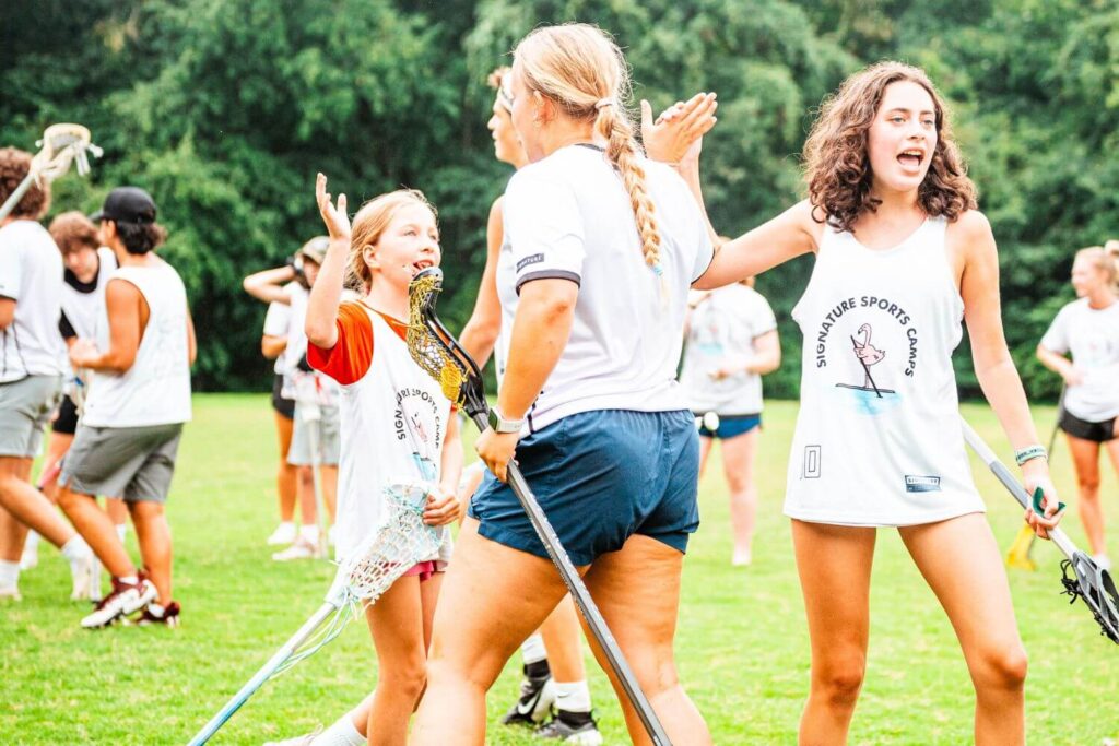 Coach at Signature Sports Camps high fiving campers after an intense lacrosse scrimmage