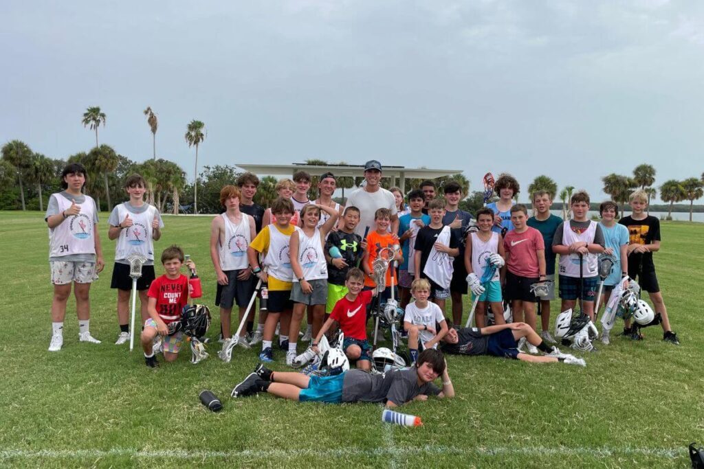 Group of young lacrosse players pose for a photo with professional lacrosse player Andrew Kew