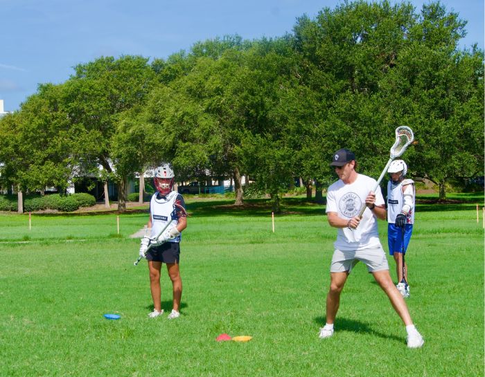 Professional Lacrosse player Andrew Kew coaching a young lacrosse player during summer camp