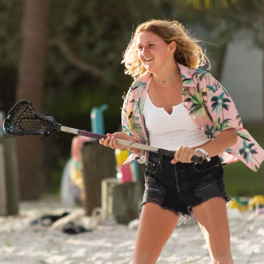 Girl on beach holding lacrosse stick