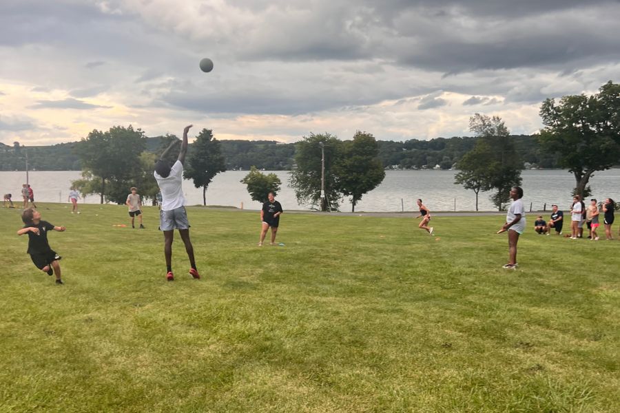 A team of kids at summer camp playing a game of kickball on a waterfront field
