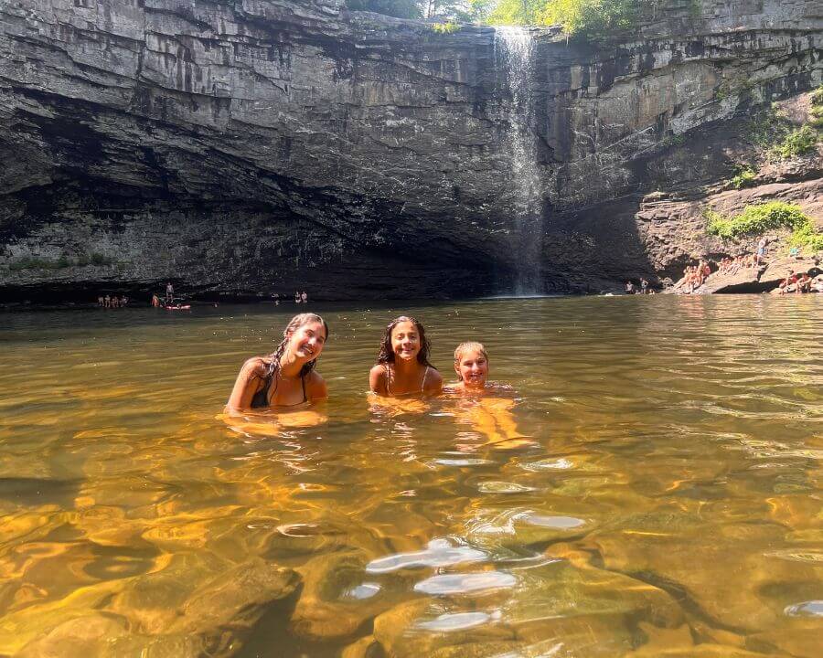 Three girls enjoying a waterfall adventure during summer Lacrosse camp