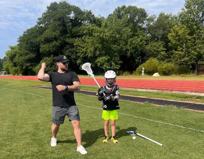 Professional lacrosse player giving instruction to a young lacrosse camper