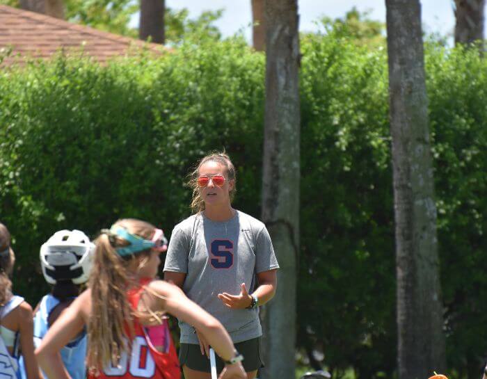 Professional lacrosse player coaching female lacrosse players during summer camp