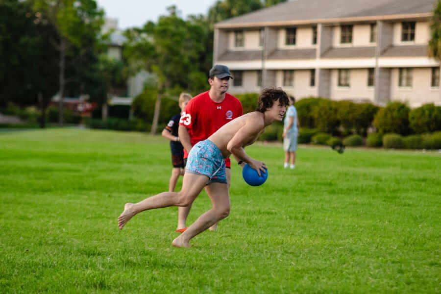 Boys playing a game of kickball on a field at summer camp