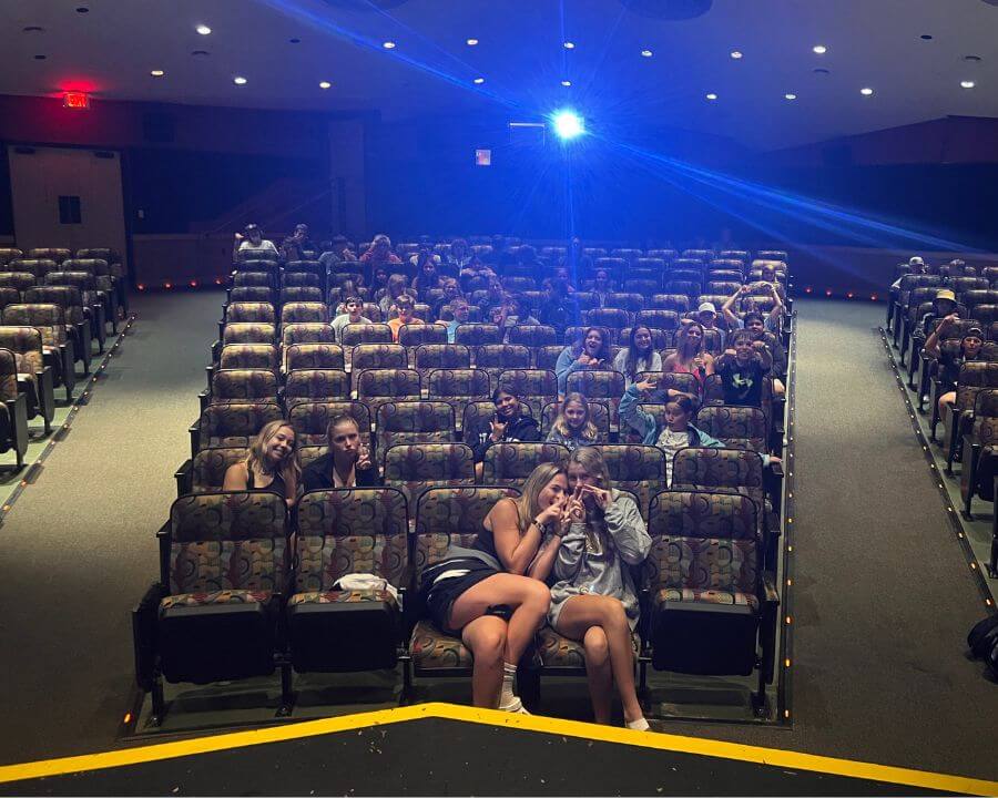 Lacrosse summer camp campers in an auditorium enjoying movie night