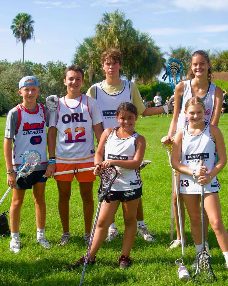 A co-ed group of lacrosse players posing while at overnight sports camp