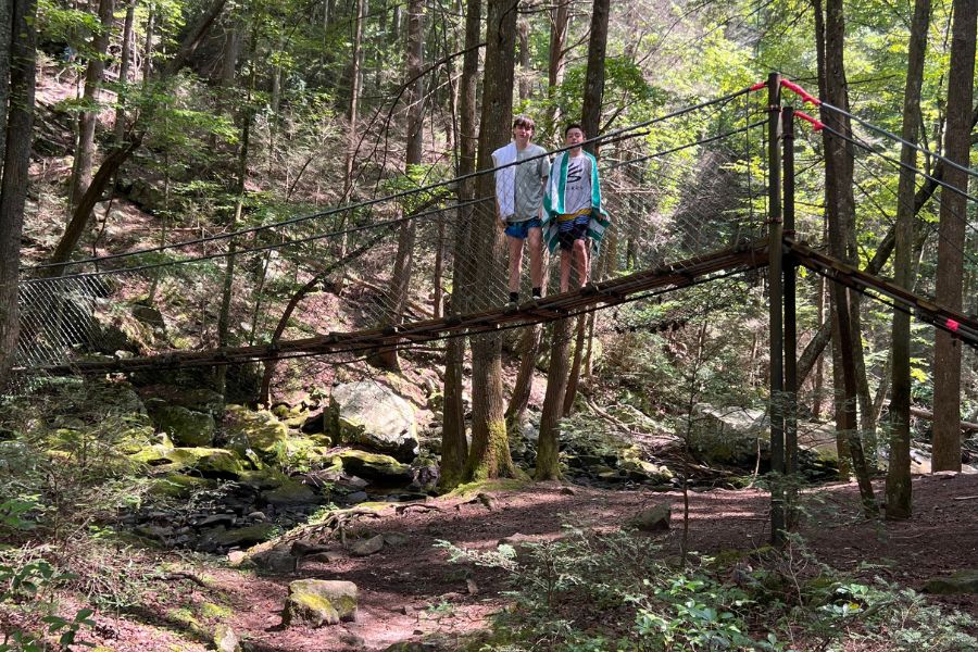 Two boys on a bridge in the woods during a summer camp hike