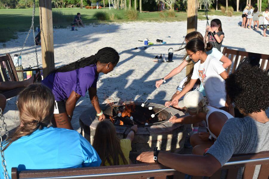 A group of summer campers gathered around a campfire roasting marshmallows