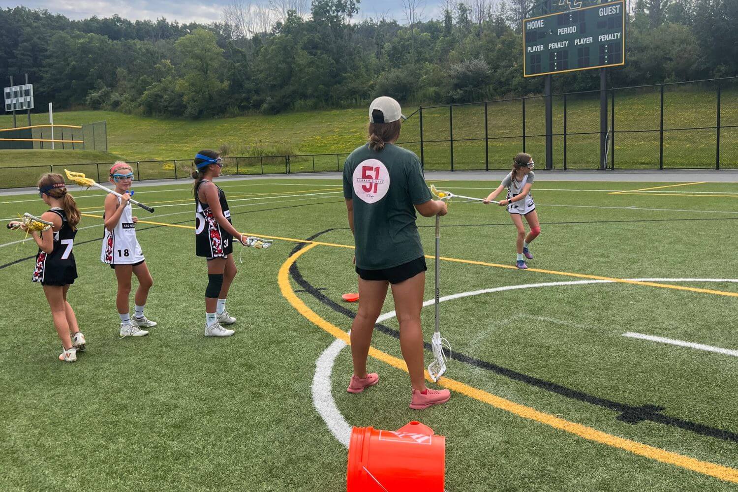 Female professional lacrosse player coaching young girls at practice during summer camp