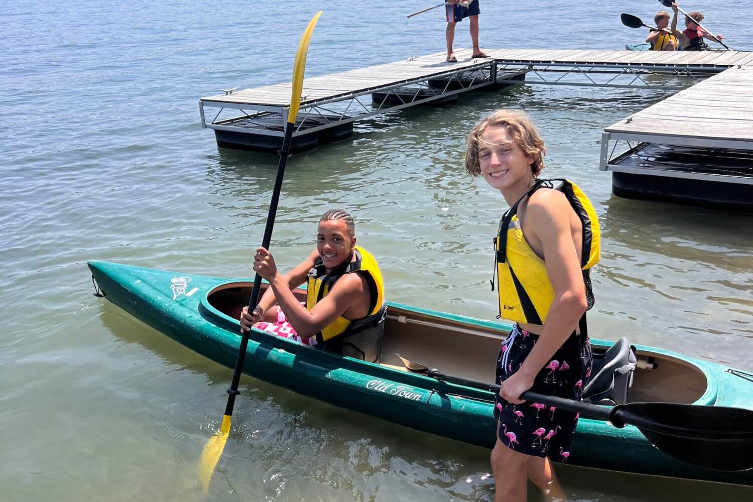 Two boys wearing yellow lifejackets are getting ready to go kayaking in Keuka Lake