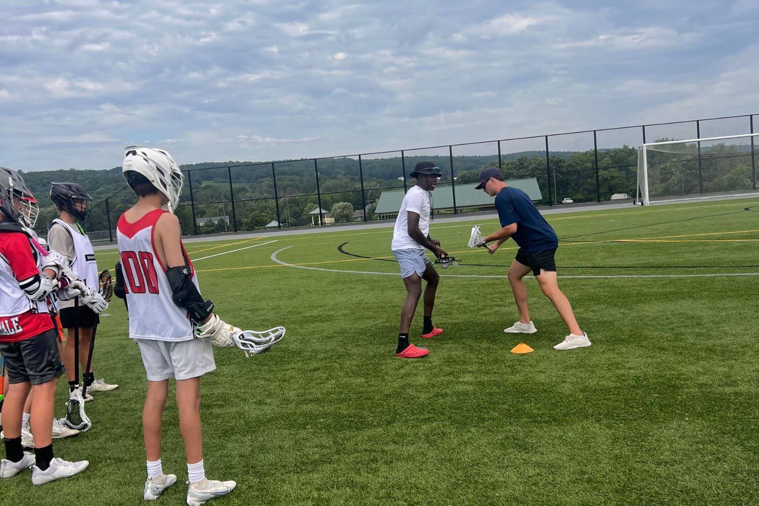 Two lacrosse coaches are giving a tutorial for a lacrosse play during practice