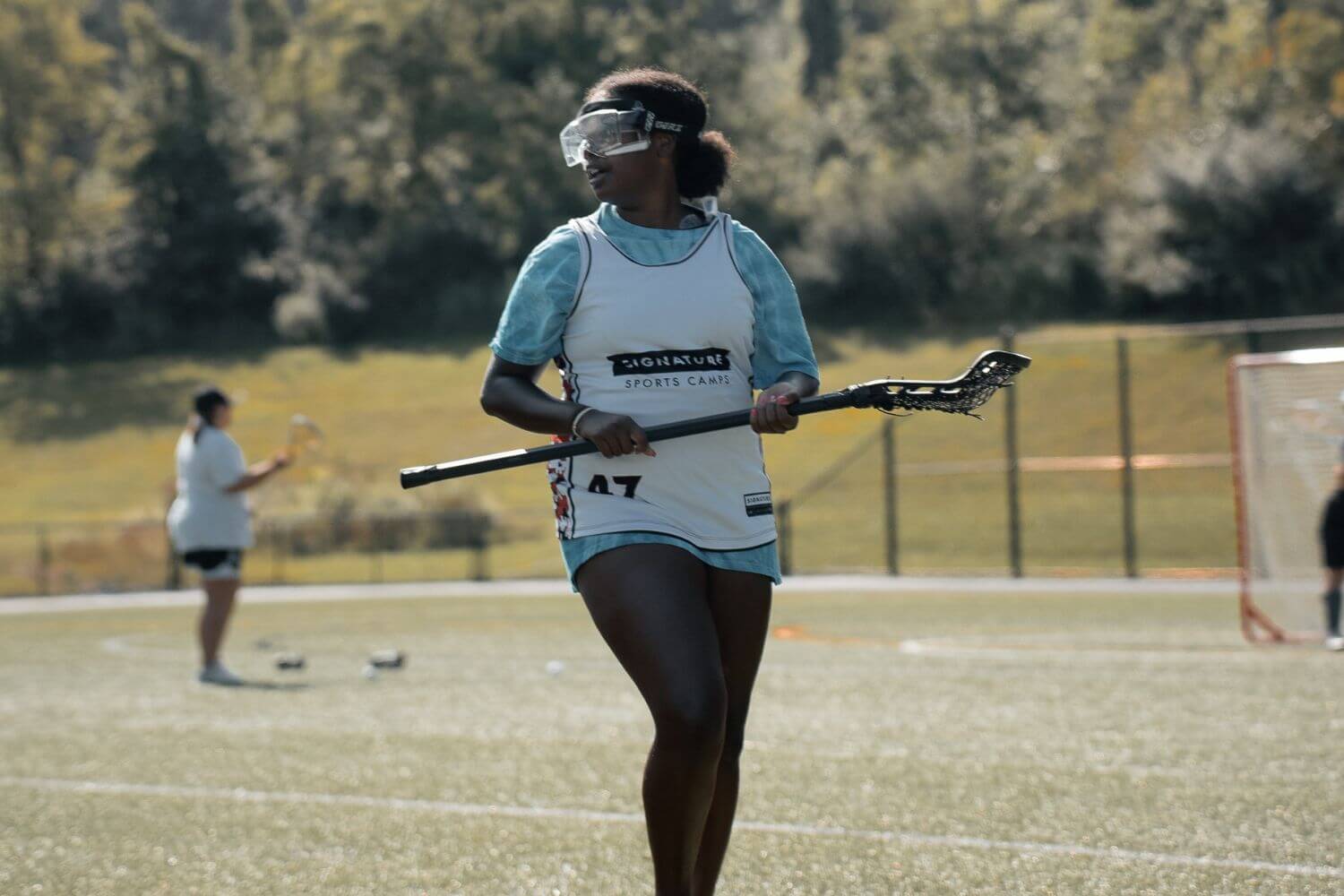 Female lacrosse player walking with her lacrosse stick