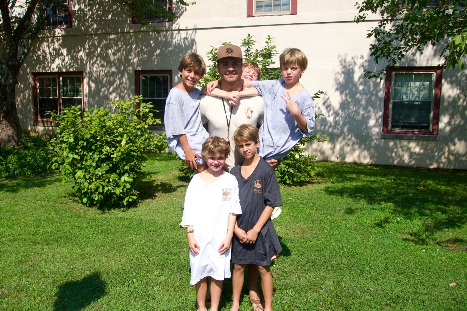 A camp counselor and young kids posing together outside for a photo