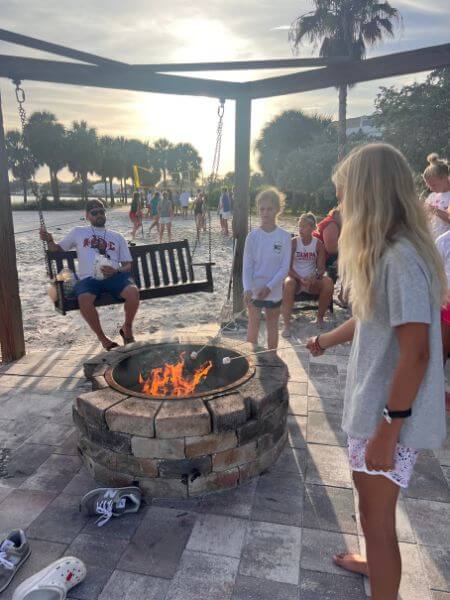 Young lacrosse campers roasting marshmallows at a sunset campfire