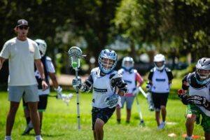 group of child lacrosse players on afield with their coach