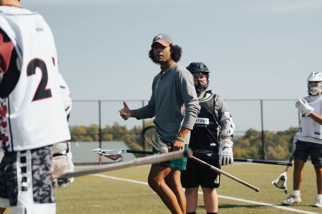 Lacrosse coach giving insight to male lacrosse players during a practice