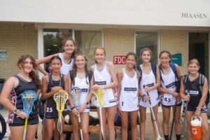 A group of female lacrosse players posing together at overnight summer sports camp