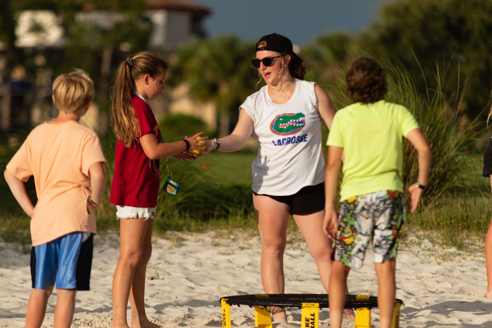 Sports camp coach and campers playing a game of Spikeball together on the beach