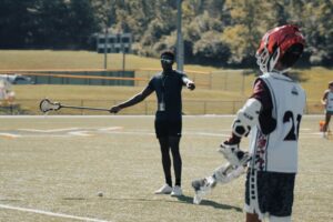 A coach at signature sports camps is giving instruction to a young lacrosse player during camp