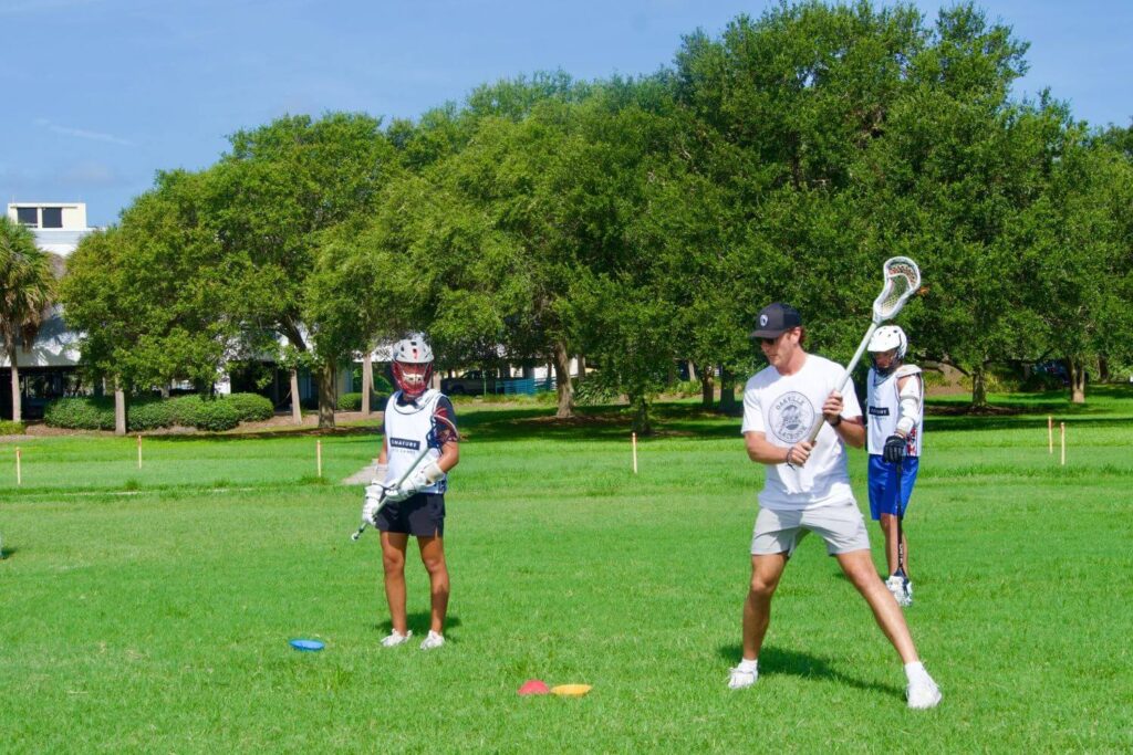 Lacrosse player at overnight sports camp receiving one on one instruction from a professional lacrosse player